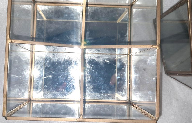 Op de afbeelding: Een set geometrische glazen en metalen displayboxen met een goudkleurig frame. De dozen zijn verdeeld in meerdere compartimenten en hebben spiegelende interieurs. Het ontwerp is modern en geschikt voor het presenteren van kleine items.