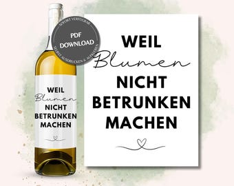 May include: A white wine bottle with a label that reads "Weil Blumen Nicht Betrunken Machen" (Because flowers don't make you drunk). The label is black and white with a heart at the bottom. The bottle is sitting on a white background.