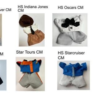 May include: Collection of miniature doll outfits, including a server uniform with a white and teal skirt, an Indiana Jones-inspired ensemble with a brown hat, and a Star Tours costume with blue and orange accents. Each outfit is designed with detailed miniature tailoring.