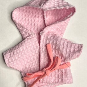K&ouml;nnte beinhalten: Ein rosa Waffel-Struktur-Bademantel mit Kapuze und einem rosa Bindeg&uuml;rtel.