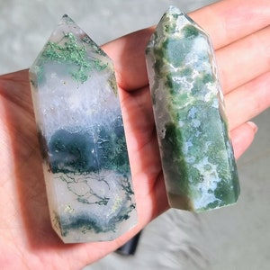 May include: Two green moss agate crystal points, one with a white and green pattern and the other with a white, green, and gold pattern.