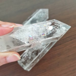 May include: Two clear quartz crystal points with iridescent rainbow colors. The points are stacked on top of each other.