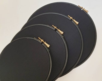 May include: Four black embroidery hoops of different sizes, with gold metal screw-on tightening rings.