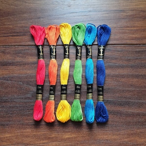 May include: Six spools of Anchor stranded cotton embroidery floss in rainbow colours: red, orange, yellow, green, blue, and indigo. Each spool is labelled with the Anchor logo and the text "8m" and a number.