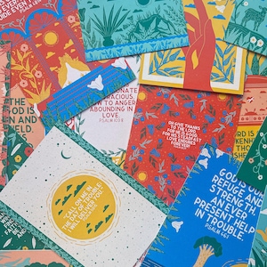 May include: A collection of colorful cards with inspirational quotes and bible verses. The cards feature a variety of illustrations, including flowers, trees, and hands. The text on the cards includes phrases like "God is our refuge and strength" and "The Lord is my shepherd, I shall not want."