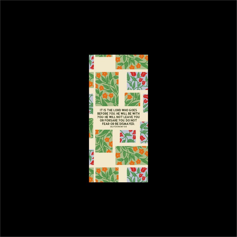 May include: A rectangular bookmark with a floral pattern in green, orange, and red on a cream background. The text "IT IS THE LORD WHO GOES BEFORE YOU... DO NOT FEAR OR BE DISMAYED" is printed on the bookmark. The bookmark is set against a black background.