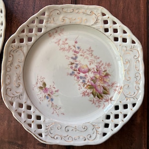 Pair of vintage 7 1/2 inch porcelain plates with pierced rim and floral design, unmarked