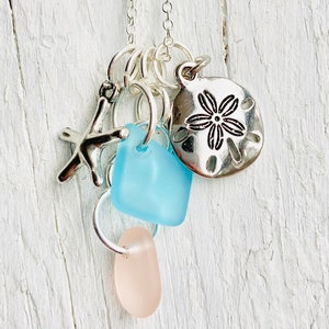 May include: A silver necklace with multiple charms, including a starfish, a blue glass charm, a pink glass charm, and a silver sand dollar charm.