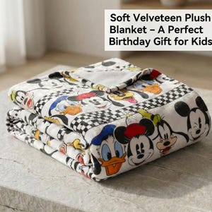 Pode incluir: Cobertor de pelúcia de veludo branco dobrado com personagens de desenhos animados. O cobertor tem uma borda xadrez em preto e branco e o texto "Soft Velveteen Plush Blanket - A Perfect Birthday Gift for Kids".