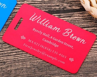 Puede incluir: Tres etiquetas de equipaje con el nombre "William Brown" impreso en blanco sobre un fondo negro, azul y rojo. Las etiquetas incluyen la dirección "Byerly Hall, 8 Garden Street, Cambridge" y la información de contacto.