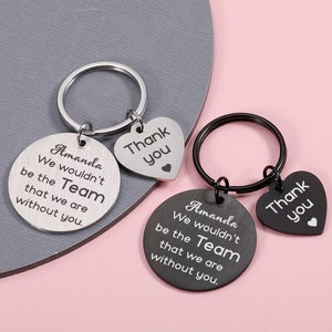 May include: Two silver keyrings with a heart-shaped charm. The charms say "Thank you". The round charms say "Amanda We wouldn't be the Team that we are without you."