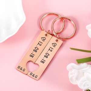May include: Two rose gold keychains with a heart cut out of the middle. The keychains are engraved with the date "18.08.17" and the initials "B&G".