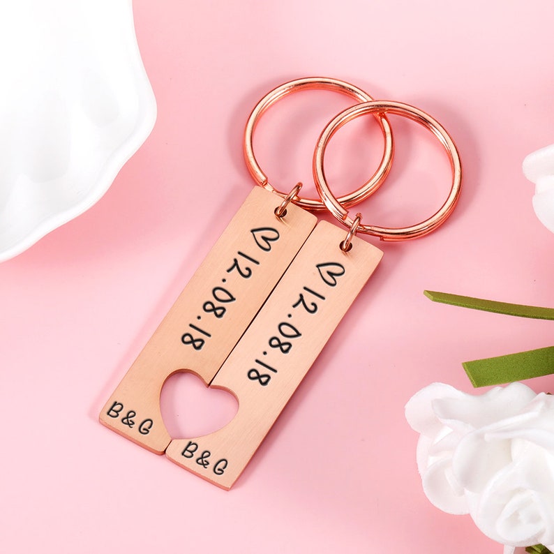 May include: Two rose gold keychains with a heart cut out of the middle. The keychains are engraved with the date "18.08.17" and the initials "B&G".