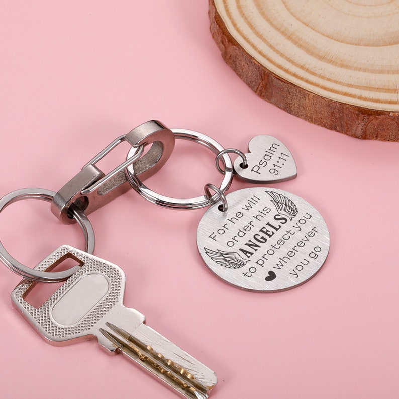 May include: Silver keychain with a round charm that reads "For he will order his angels to protect you wherever you go" and a heart-shaped charm that reads "Psalm 91:11".