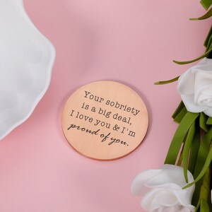 May include: A round wooden coaster with the text "Your sobriety is a big deal, I love you & I'm proud of you."