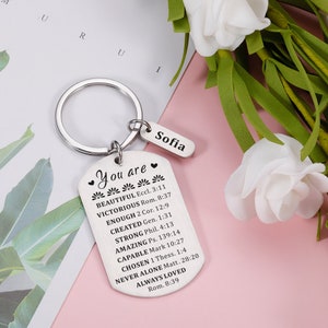 Puede incluir: Llavero de plata con una etiqueta en forma de coraz&oacute;n que dice "You are" seguida de una lista de afirmaciones positivas y vers&iacute;culos b&iacute;blicos. La etiqueta est&aacute; unida a un anillo de plata con una etiqueta m&aacute;s peque&ntilde;a que dice "Sofia".