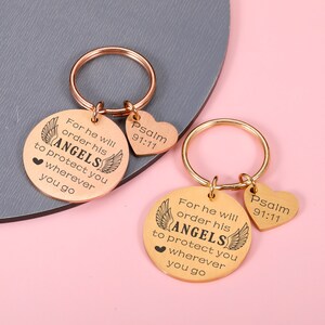 May include: Two gold-tone keychains with round tags and heart-shaped charms. The tags feature the text "For he will order his ANGELS to protect you wherever you go" and "Psalm 91:11".