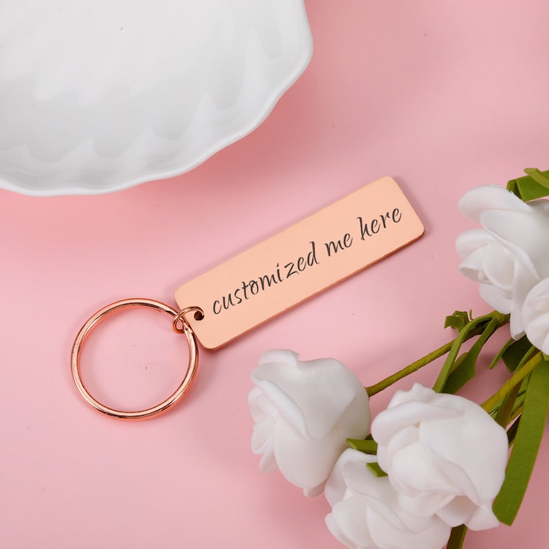 May include: A rose gold keyring with a rectangular tag that says "customized me here".