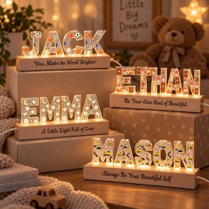 May include: Four illuminated wooden name signs featuring acrylic letters with various patterns. The signs display the names JACK with sports motifs, ETHAN with forest animals, EMMA with floral designs, and MASON with construction vehicles.