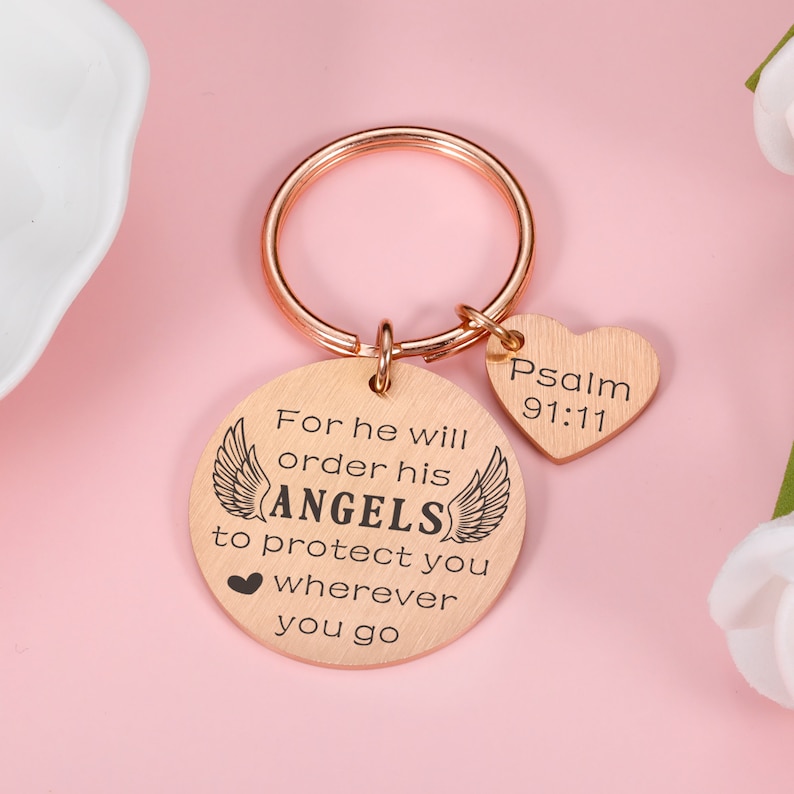 May include: Rose gold keychain with a round charm that reads "For he will order his ANGELS to protect you wherever you go" and a heart charm that reads "Psalm 91:11".