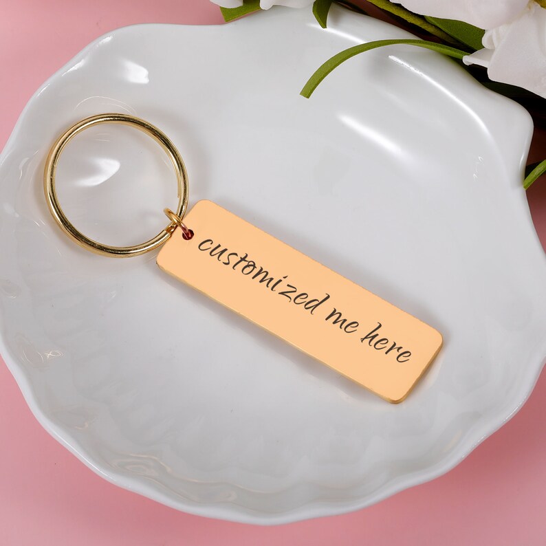 May include: Gold-toned keychain with a rectangular tag that says "customized me here" in cursive script.