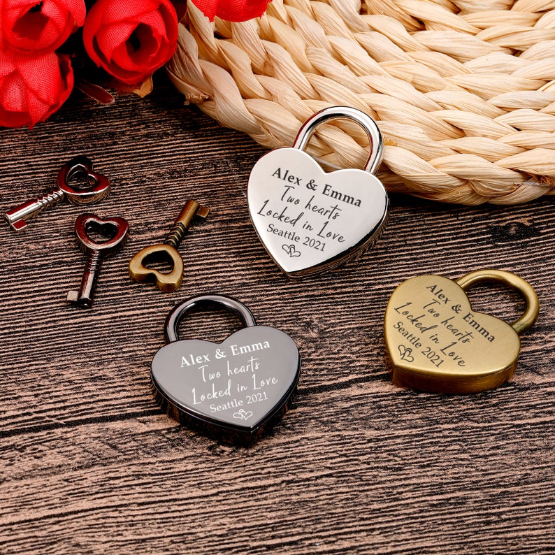 May include: Three heart-shaped padlocks with keys, each engraved with "Alex & Emma Two hearts Locked in Love Seattle 2021". One padlock is silver, one is gold, and one is black.