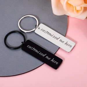 May include: Two silver keyrings with black and white rectangular tags. The tags have the text "customized me here" written on them.