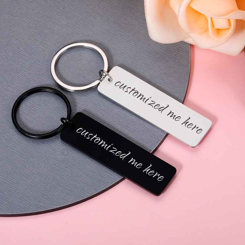 May include: Two silver keyrings with black and white rectangular tags. The tags have the text "customized me here" written on them.