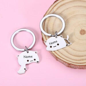 May include: Two silver keychains with cat-shaped charms. Each charm has a space for a name, and the text "Name" is engraved on each charm.