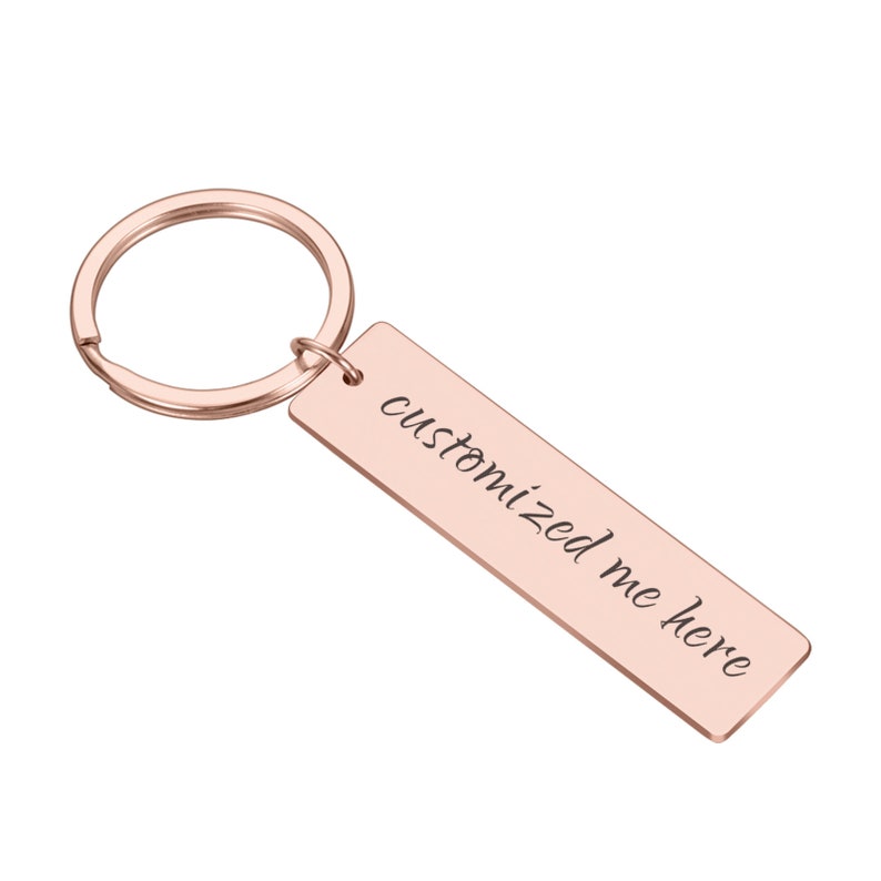May include: Rose gold metal keychain with a rectangular tag that says "customized me here" in cursive.