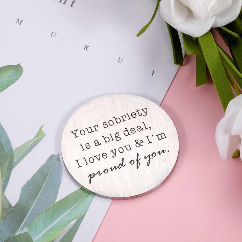 May include: A silver round disc with the text "Your sobriety is a big deal, I love you & I'm proud of you." engraved on it.