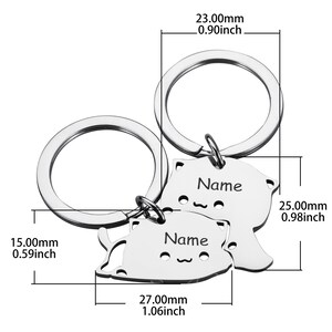 May include: Two silver keychains with cat-shaped charms. Each charm has a space for engraving a name. The charms are 0.98 inches tall and 1.06 inches wide.