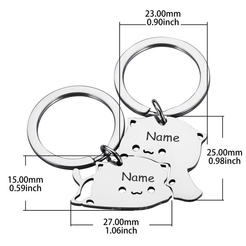 May include: Two silver keychains with cat-shaped charms. Each charm has a space for engraving a name. The charms are 0.98 inches tall and 1.06 inches wide.