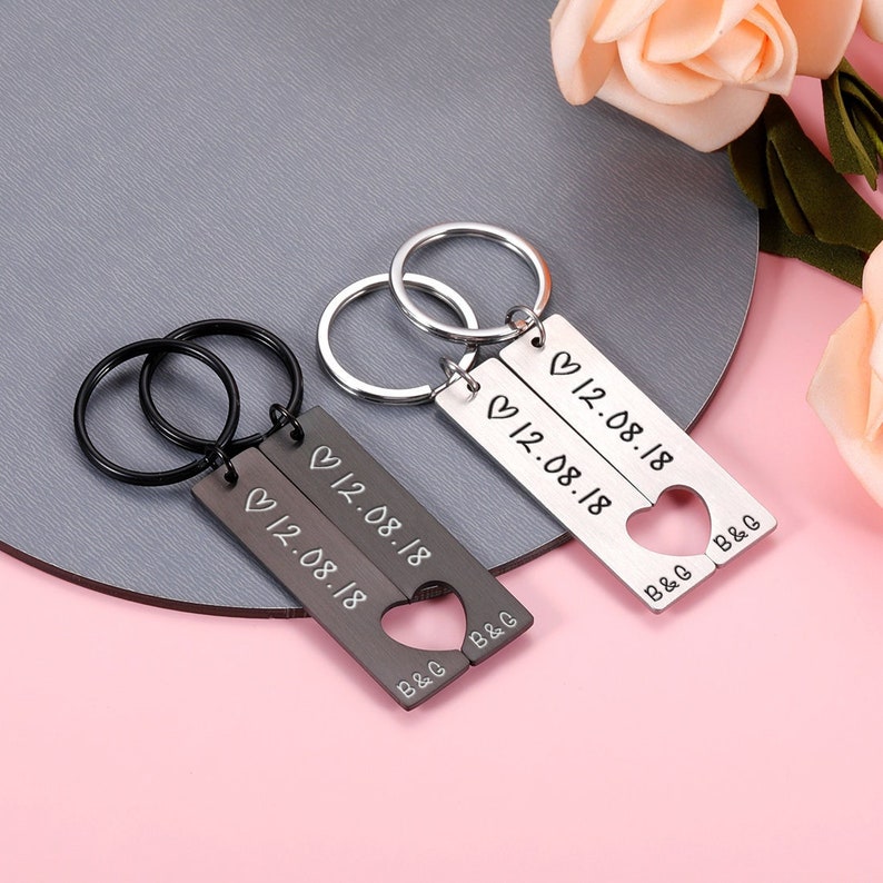 May include: Two silver keychains with heart-shaped cutouts. Each keychain has a rectangular tag with the text "12.08.18" and "B&G" engraved on it.