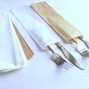 May include: A stack of white and brown paper cutlery sleeves. Two sleeves contain a fork and knife. The silverware is stainless steel. The sleeves are rectangular and folded at the bottom. The background is white.