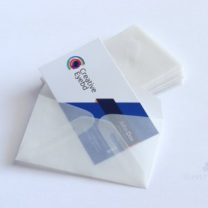 May include: A stack of white business cards with the Creative Eyebd logo and a sample card in a translucent envelope. The business card has the name "John Doe" printed on it. The background is plain white.