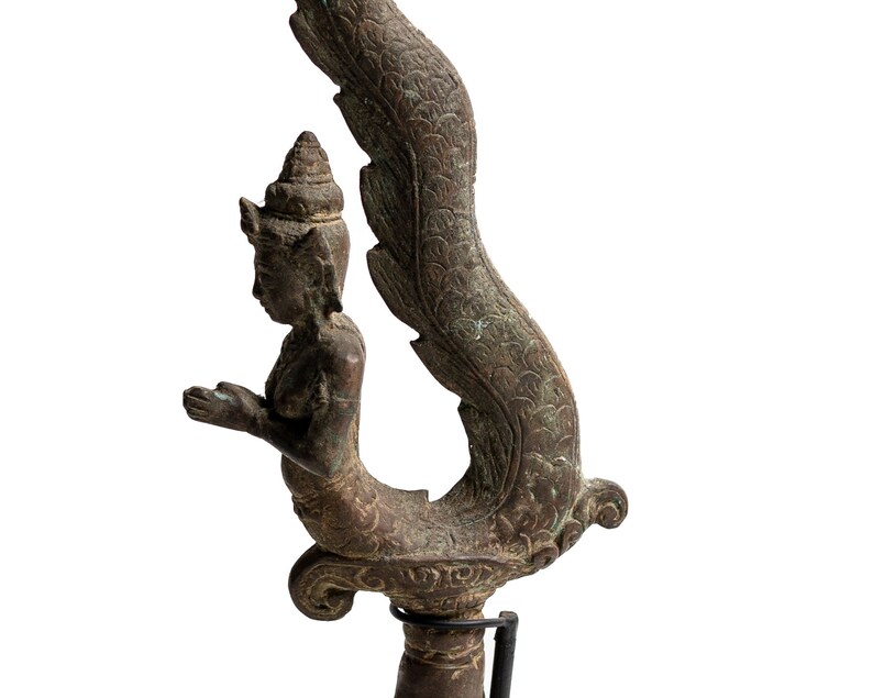 May include: A bronze sculpture of a mythical creature with a human-like torso and a tail that resembles a serpent. The creature is depicted in a kneeling position with its hands clasped together in prayer. The sculpture is intricately detailed and has a rich patina.