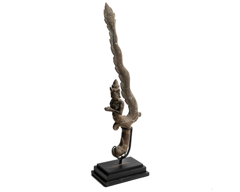 May include: A bronze sculpture of a mythical creature with wings and a human-like figure. The sculpture is mounted on a black wooden base.