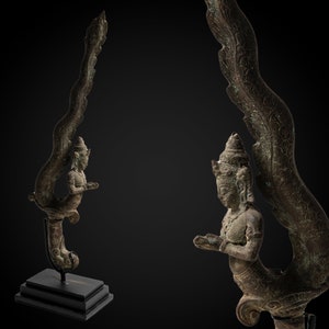 May include: A bronze sculpture of a mythical creature with a human torso and a bird-like tail. The creature is depicted in a kneeling position with its wings spread out. The sculpture is detailed with intricate carvings and has a dark patina.
