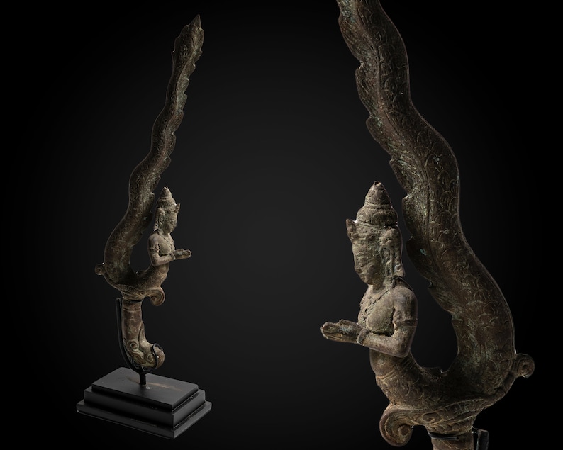 May include: A bronze sculpture of a mythical creature with a human torso and a bird-like tail. The creature is depicted in a kneeling position with its wings spread out. The sculpture is detailed with intricate carvings and has a dark patina.
