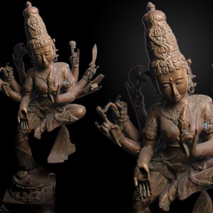 Puede incluir: Una estatua de bronce de una deidad de múltiples brazos con una corona y detalles intrincados. La deidad está representada en una pose de baile con múltiples manos en varios mudras.