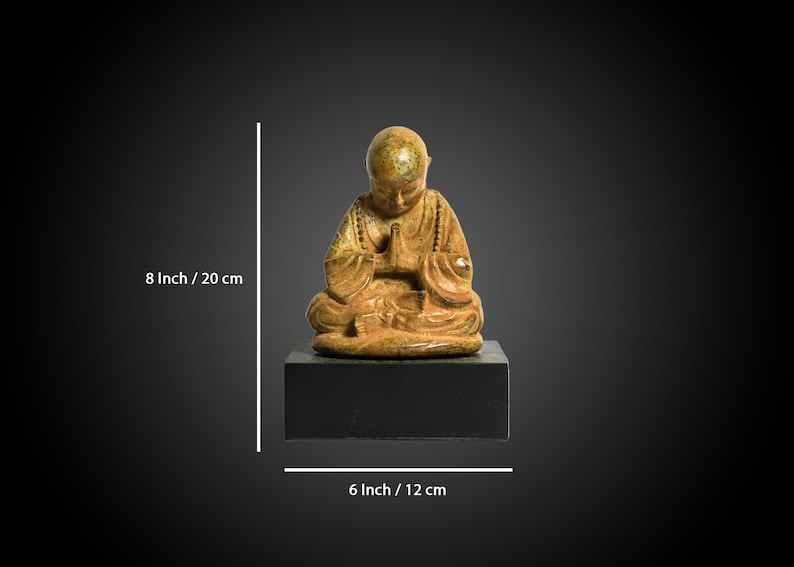 May include: A small, gold-colored ceramic statue of a seated Buddha figure with hands in prayer position. The statue is 8 inches tall and 6 inches wide.