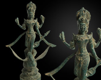 May include: A green bronze statue of a four-armed deity standing on a bird. The deity is wearing a crown and elaborate jewelry. The statue is intricately detailed and has a weathered patina.