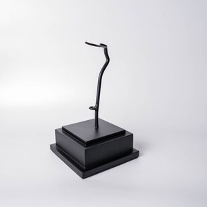 May include: A black metal display stand with a curved arm, perfect for showcasing small items like figurines or jewelry.