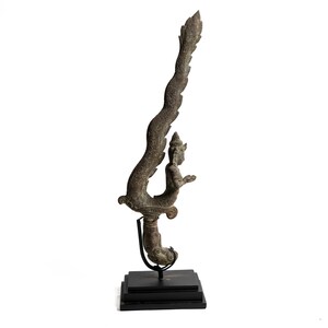 May include: A bronze sculpture of a mythical creature with a human-like torso and a serpent-like tail. The sculpture is mounted on a black stand.