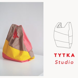 May include: A color block shopping bag with a yellow, pink, and brown design. The bag is folded and has a simple design. The bag is made by TYTTKA Studio.