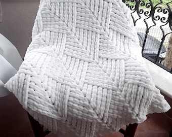 May include: White knitted throw blanket with a woven pattern. The blanket is soft and fluffy, and it is draped over a chair.