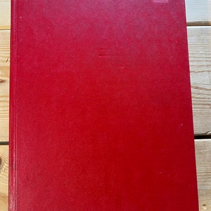 May include: A red leather-bound book with a small white sticker on the top right corner.
