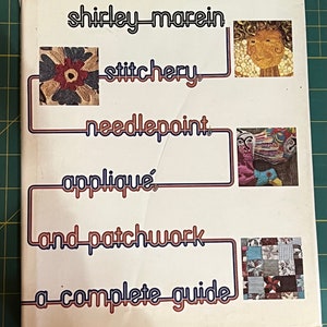 May include: A book titled "Shirley Marein Stitchery, Needlepoint, Appliqué, and Patchwork: A Complete Guide" with colorful illustrations of various needlework techniques.