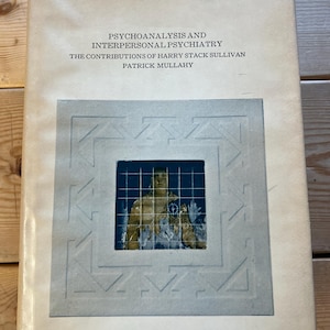 May include: Book cover with a white background and blue and white geometric design. The title is "Psychoanalysis and Interpersonal Psychiatry: The Contributions of Harry Stack Sullivan" by Patrick Mullahy.